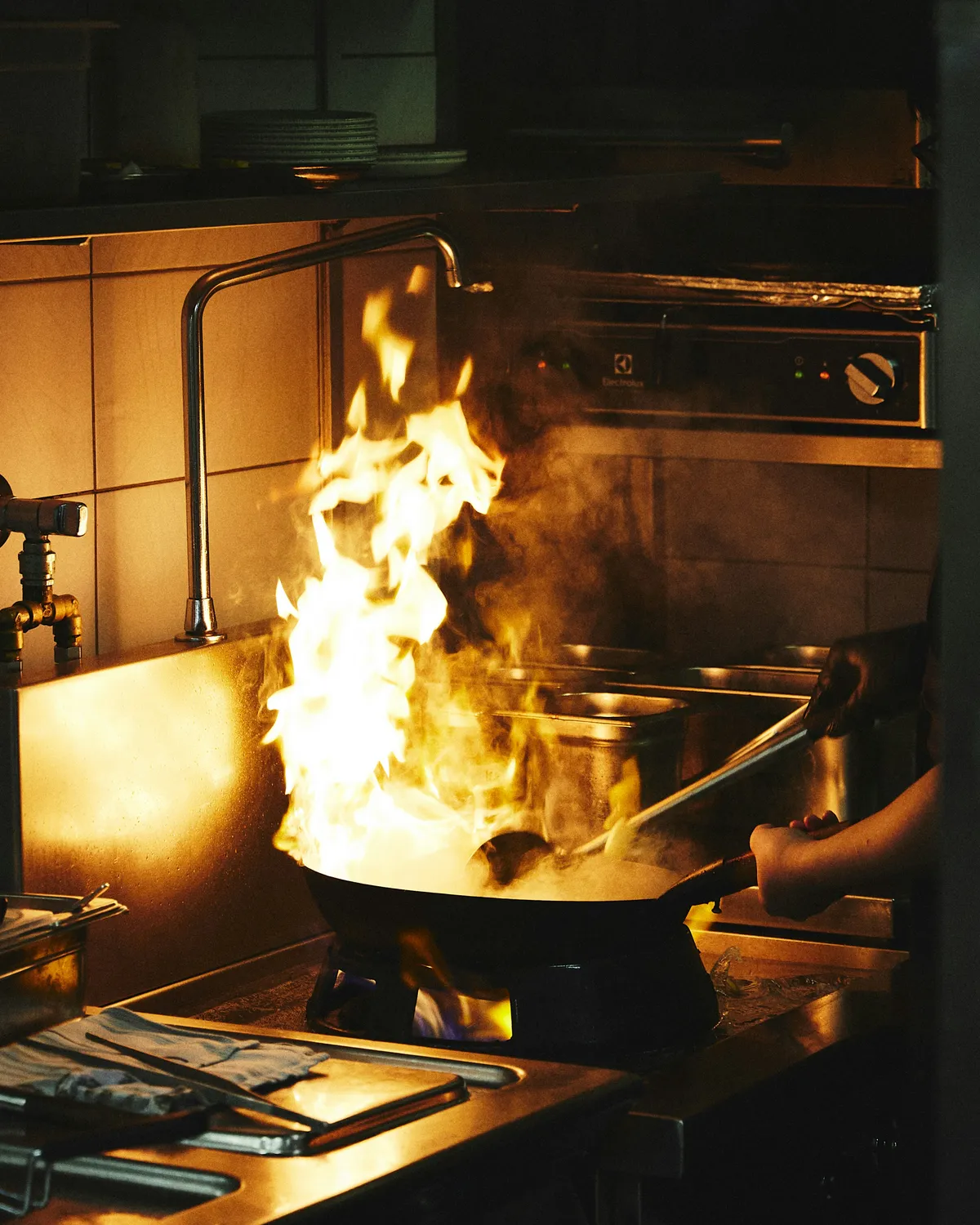 Flambierender Wok über offener Flamme in der Küche